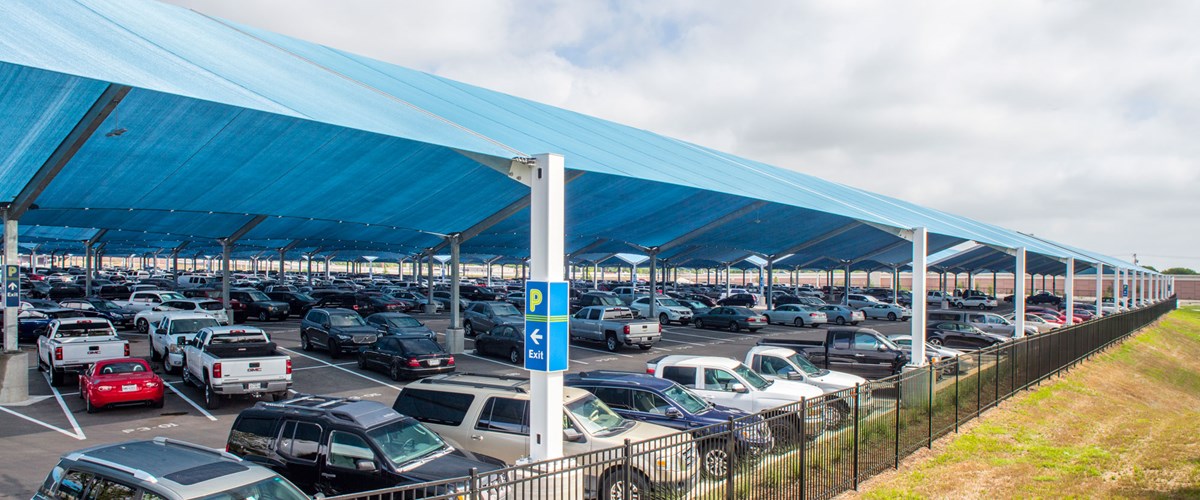 cars parked underneath outdoor parking lot shades thumbnail