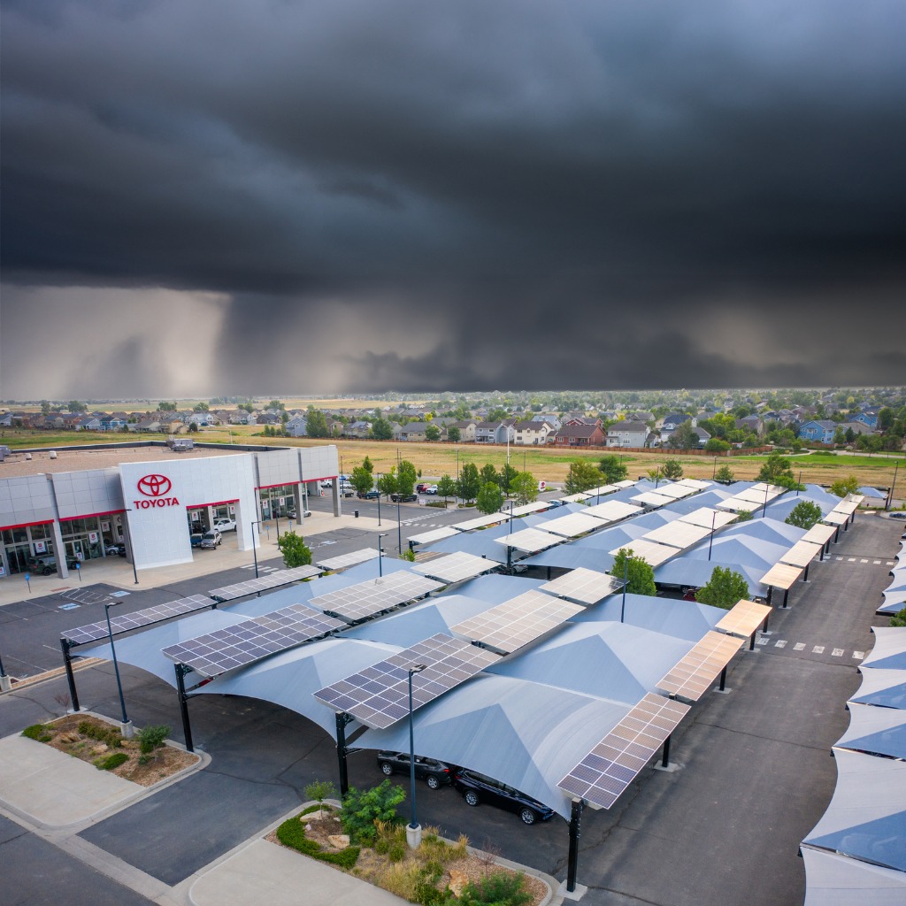 stormy dark skies over car dealership, cars protected by shade structures